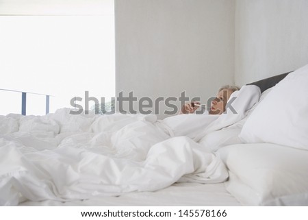 Middle aged woman checking her body temperature with thermometer in bed