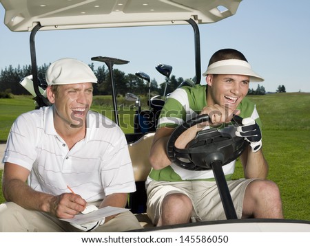 Cheerful young male golfers sitting in golf cart at course