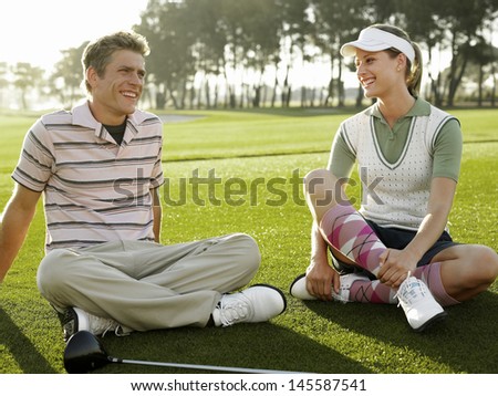 Full length of two young golfers sitting on golf course