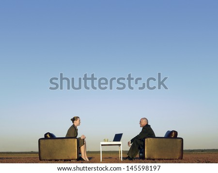 Side view of business people on armchairs communicating on field