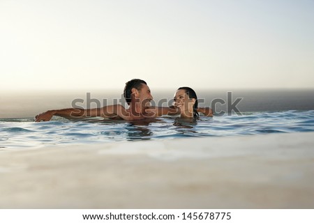 Happy couple relaxing in infinity pool at resort