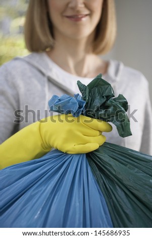 Closeup of a woman in rubber gloves holding garbage bag