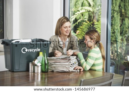 Woman and girl preparing waste paper for recycling at home