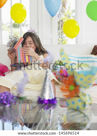 Cheerful young girl opening birthday presents in house