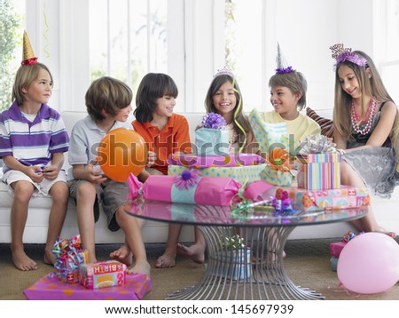 Group of cheerful children sitting on sofa at birthday party