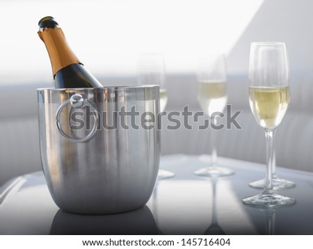 Flutes with champagne bottle in ice bucket on table