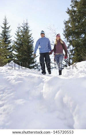 Full length low angle view of a couple descending snow covered hill