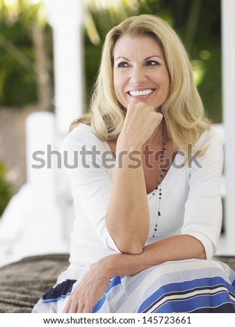 Smiling middle aged woman sitting on verandah and looking away