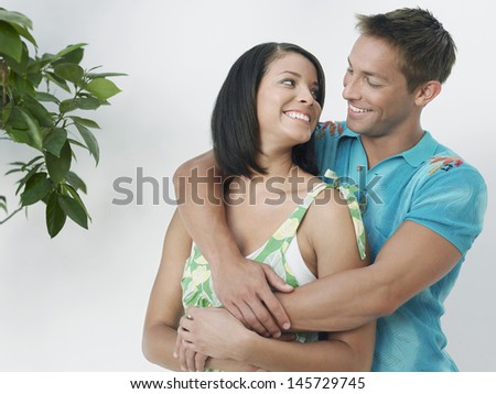 Affectionate young man embracing woman from behind