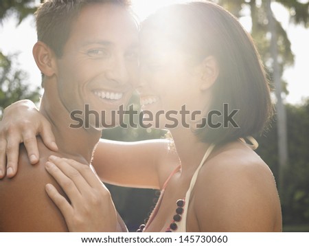 Side view portrait of a happy young couple with arms around in garden