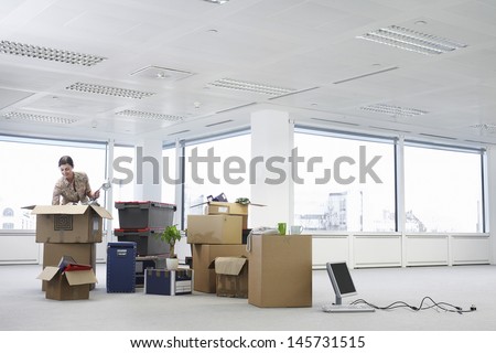 Young businesswoman unpacking cartons in an empty office space