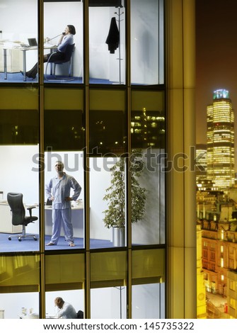 Three business people working late night in different office blocks