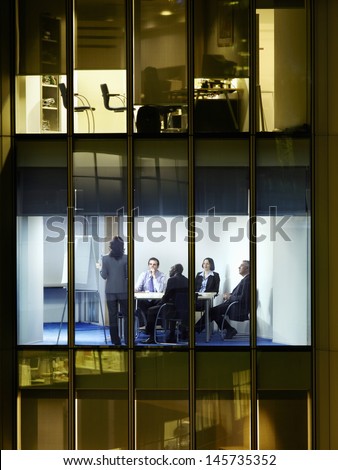 View of business people in a meeting through window at night
