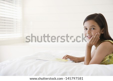 Portrait of relaxed little girl with story book in bed