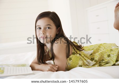 Portrait of little girl with story book in bed