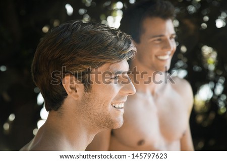 Side view of smiling young man with friend in background