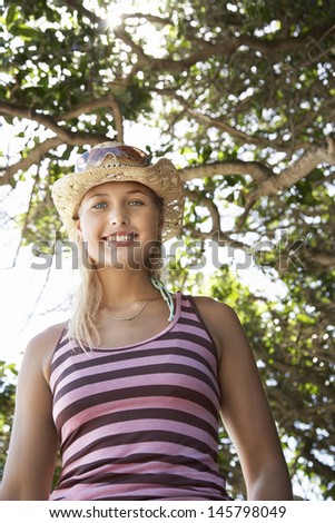 Portrait of beautiful young woman in sunhat under tree