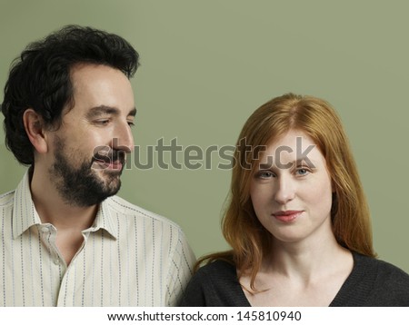 Closeup of happy young man looking at beautiful woman on colored background