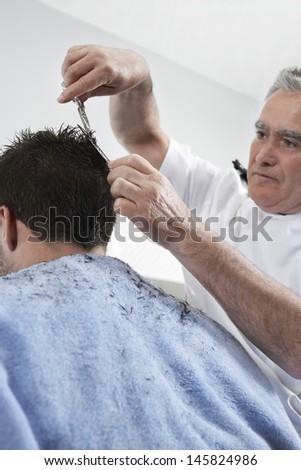 Senior hairdresser cutting man\'s hair in barber shop