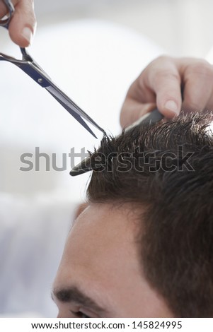 Closeup of man getting an haircut from barber in salon