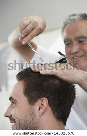 Closeup of happy man getting an haircut from barber in hair salon