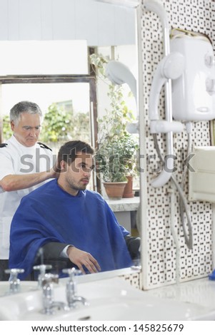Senior hairdresser cutting man\'s hair in barber shop
