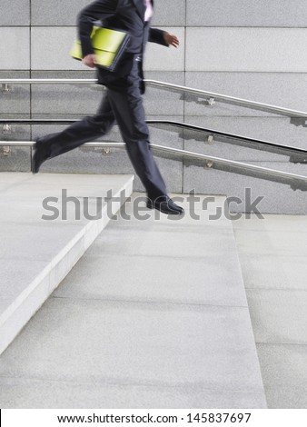 Lowsection side view of a young businessman running down steps outdoors