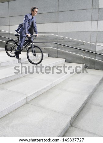 Side view of a businessman riding bicycle down steps