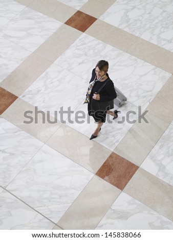Elevated view of a businesswoman walking with suitcase on tiled floor