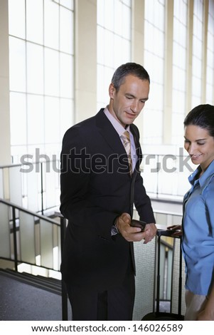 Businessman showing woman mobile phone in the airport lobby