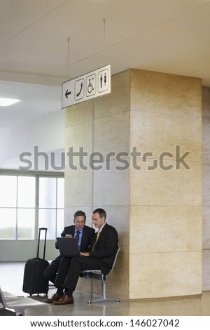 Two businessmen using laptop in the airport lobby