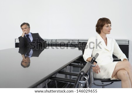 Serious businesswoman with back to businessman at conference table