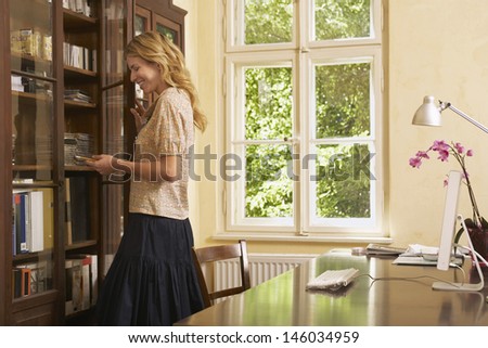 Side view of a young blond woman looking in cabinet in study room
