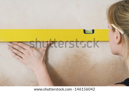 Closeup rear view of a blond young woman using spirit level
