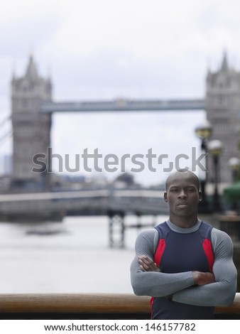 Portrait of a serious young African American man with arms crossed in front of Tower Bridge in England