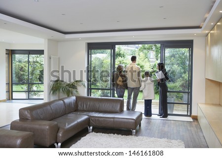 Rear view of parents with daughter and female estate agent at new property