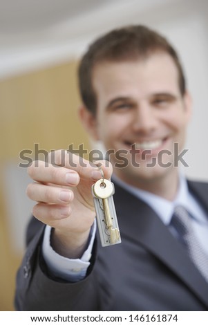 Blurred happy male real estate agent holding out house key