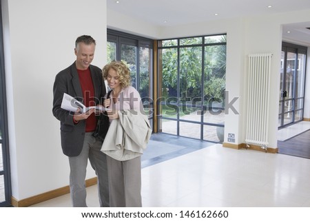 Happy couple reading brochure in new property