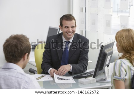Friendly male real estate agent with a couple in the office