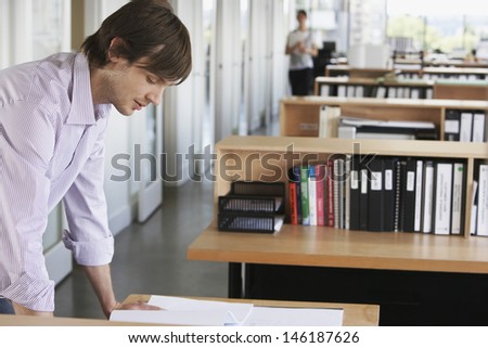 Side view of a young male architect studying blueprint in office
