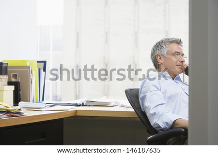 Middle aged businessman using landline phone in the office