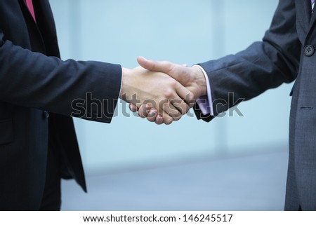 Mid section of business people shaking hands