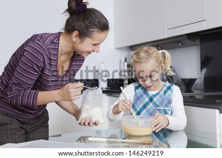 Happy mother and daughter baking together in kitchen