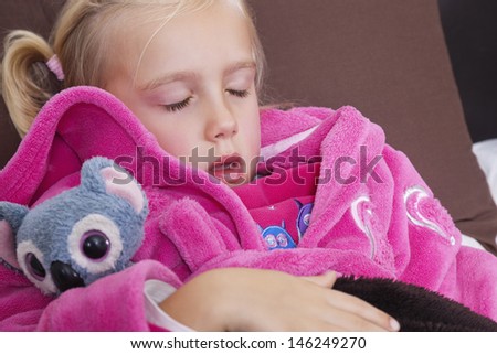 Cute little girl in pink jacket sleeping with teddy bear