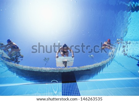 Low angle view of female swimmers ready to dive in pool from starting position