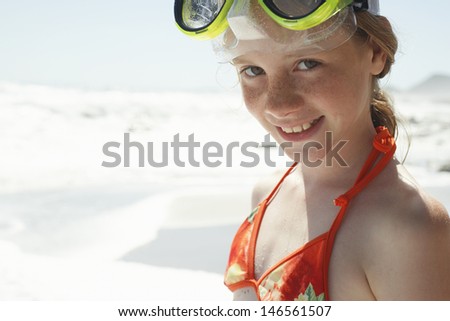Side view of little girl wearing goggles looking away at beach