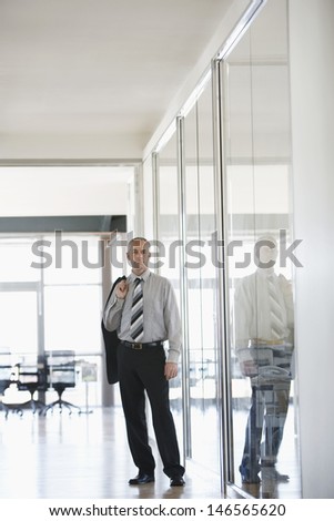 Portrait of confident middle aged businessman standing in office corridor