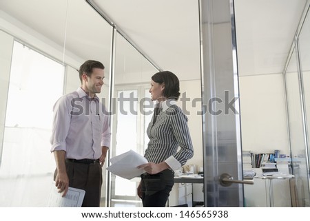 Happy businessman and businesswoman with paperwork taking in office