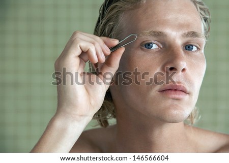 Closeup portrait of handsome young man plucking eyebrows