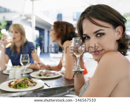 Portrait of beautiful young woman with friends at outdoor cafe